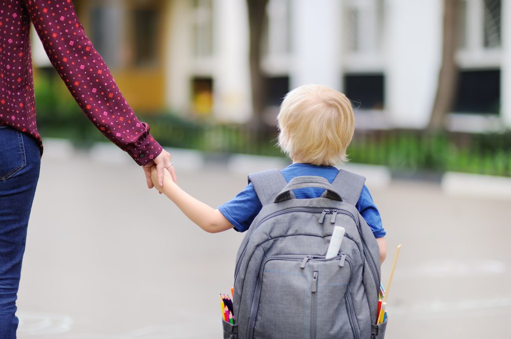 Back to school concept. Little pupil with his young mother. First day of primary school. Education for small kids.